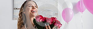 Happy woman holding roses near balloons