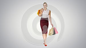Happy woman holding shopping bags, smiling and walking on gradient background.
