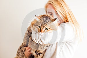 Happy woman holding siberian cat and kissing him