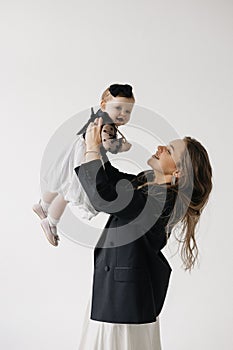 A happy woman is holding a smiling baby girl in black and white outerwear