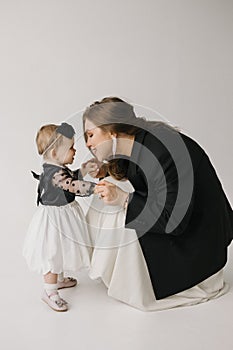 A happy woman is holding a smiling baby girl in black and white outerwear