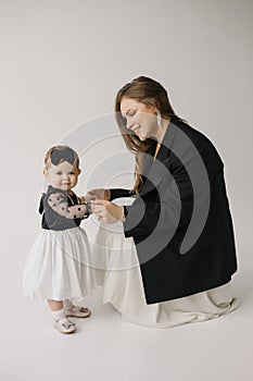 A happy woman is holding a smiling baby girl in black and white outerwear