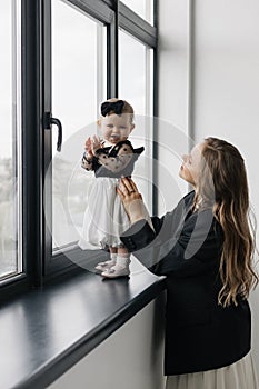 A happy woman is holding a smiling baby girl in black and white outerwear