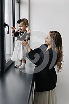 A happy woman is holding a smiling baby girl in black and white outerwear