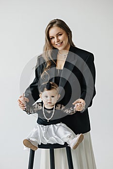 A happy woman is holding a smiling baby girl in black and white outerwear