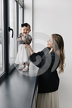 A happy woman is holding a smiling baby girl in black and white outerwear