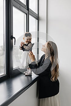 A happy woman is holding a smiling baby girl in black and white outerwear