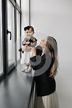 A happy woman is holding a smiling baby girl in black and white outerwear