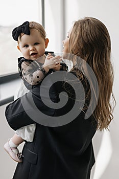 A happy woman is holding a smiling baby girl in black and white outerwear