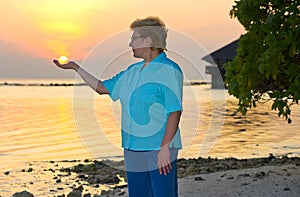 Happy woman holding sun on beach