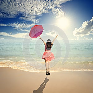 Happy Woman holding umbrella and Jumping in Sea sun sky