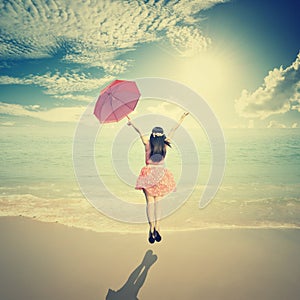 Happy Woman holding umbrella and Jumping in Sea sun sky