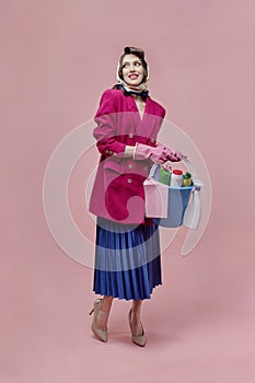 A happy woman holds a bucket of cleaning tools in her hands. Bright makeup.