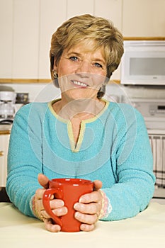 Happy woman holds a coffee mug in her kitchen