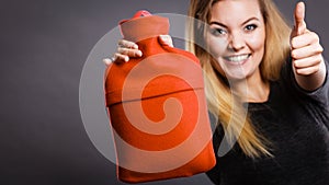 Happy woman holds hot water bottle