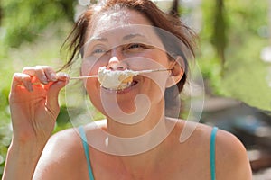 A happy woman holds a marshmallow stick