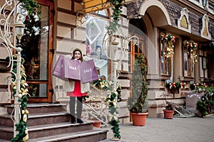 Happy woman holds paperbags with symbol of sale in the stores with sales at Christmas, around the city. Concept of shopping,