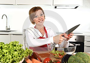 Happy woman at home kitchen preparing vegetable salad with lettuce carrots and slicing tomato