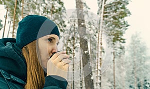 Happy woman with hot drink in tumbler outdoors in winter park