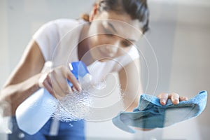 Happy woman house wife cleaning glass table in home