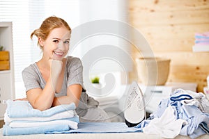 Happy woman housewife ironing clothes in laundry at home