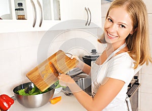 Happy woman housewife preparing salad in the kitchen