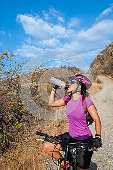 Happy woman hydrates by her bike on a sunny day. Active people. Healthy lifestyle concept photo