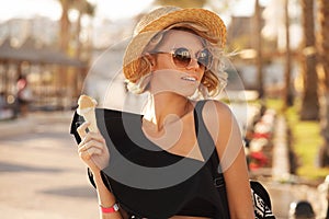 Happy woman with ice cream wearing sunglasses and beach hat having summer fun during travel holidays vacation