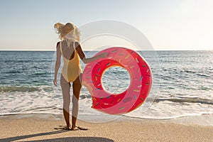 Happy woman with inflatable donut on a tropical beach. Summer vacation concept