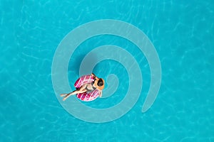 Happy woman with inflatable ring in swimming pool, top view. Summer vacation