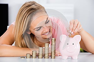 Happy Woman Inserting Coin In The Piggybank