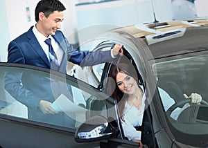 Happy woman inside car in auto show or salon