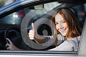 Happy woman inside a car gesturing thumb up