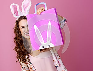 Happy woman isolated on pink hiding behind Easter shopping bag