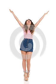 Happy Woman In Jeans Mini Skirt Is Standing With Arms Outstretched And Looking Up