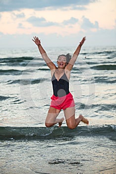 Happy woman jump in the air on the beach at sea