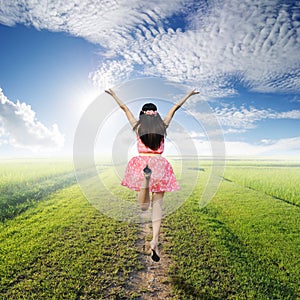 Happy woman jump in green rice fields and blue sk
