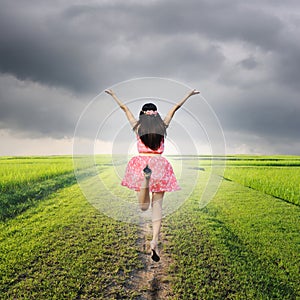 Happy woman jump in green rice fields and rainclouds photo