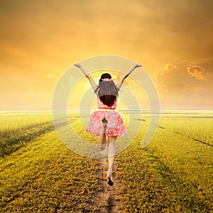 Happy woman jump in green rice fields and sunset