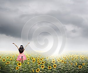 Happy woman jump in sunflower fields and rainclouds