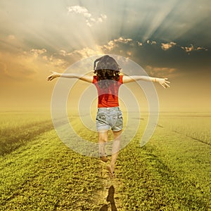 Happy woman jump on way of green grass and sunset