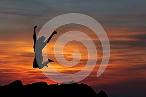 Happy woman jumping against beautiful sunset.