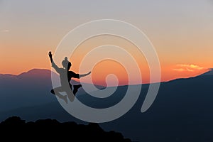 Happy woman jumping against beautiful sunset.