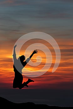 Happy woman jumping against beautiful sunset.