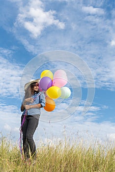 Happy woman jumping with air balloons on the meadow