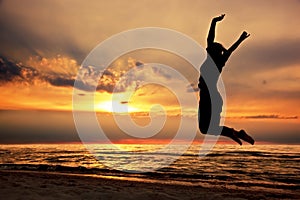 Šťastný žena skákání na pláž na západ slunce 