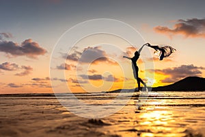 Happy woman jumping on the beach and water splash. Mountain, sea water and beautiful cloud is landscape