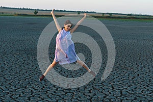 Happy woman jumping on dry lake