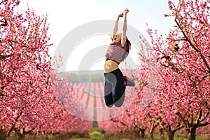 Happy woman jumping in a flowered field in spring