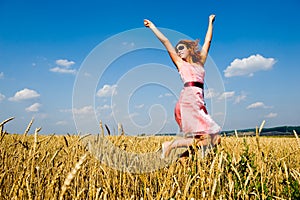 Happy woman jumping in golden field